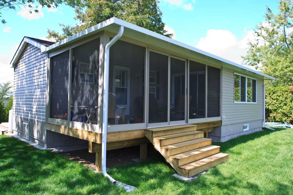 Custom design-build screen room with glass panels and outdoor deck